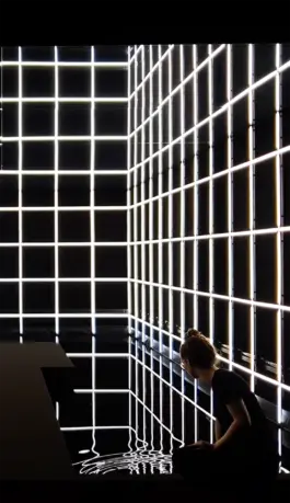 A women sitting inside an immersive light art installation made out a light grid by the artist jacqueline hen 