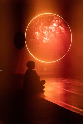 a women sitting on the floor in front of a glowing light art installtion by artist jacqueline hen 